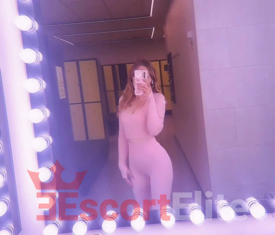 Gabi – moderne zarte Begleitung Wien Escort Wien Gabi im Spiegel mit sanftem Licht und pinkem Outfit